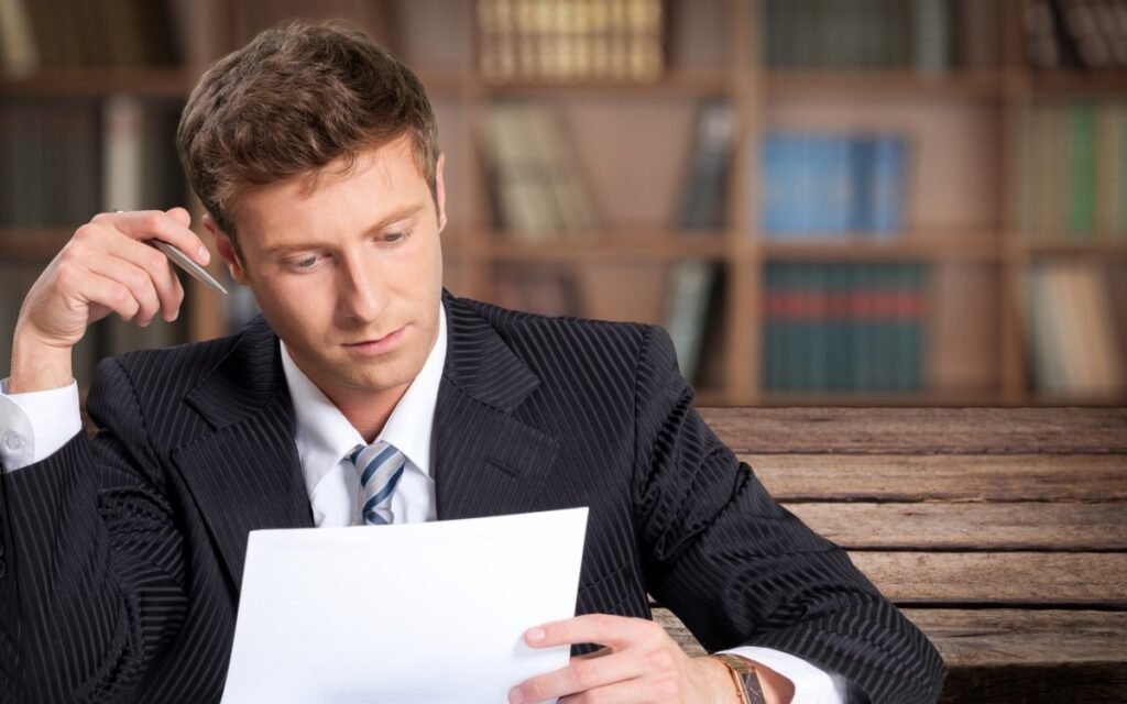 Businessman reviewing a report while holding a pen.